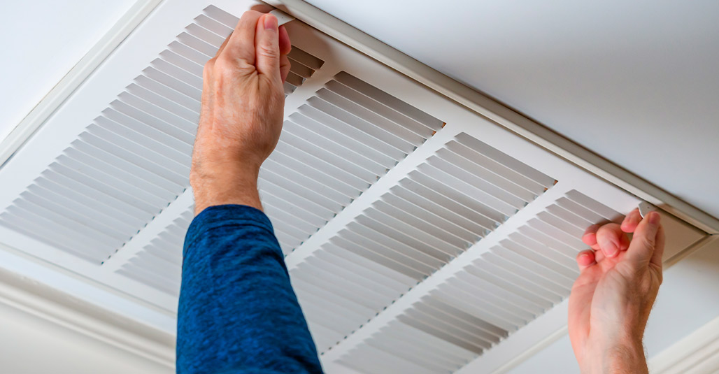 Individual holding an air duct indoors, illustrating steps to prepare a home for cooler weather in South Texas.