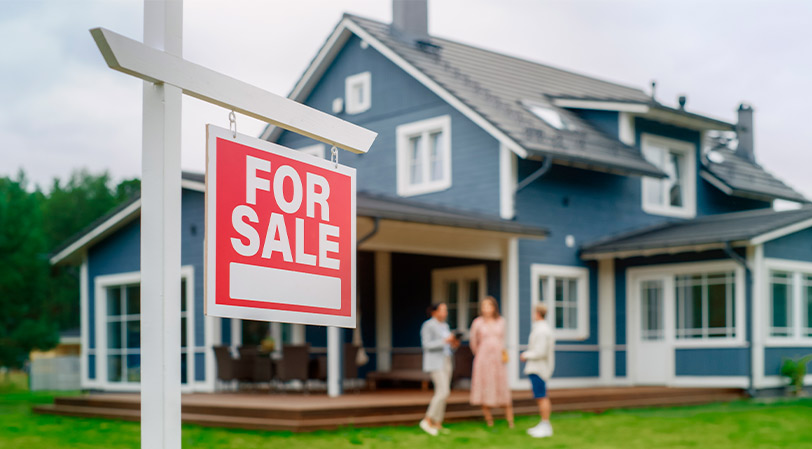 A couple and a real estate agent are in front of a house for sale, exploring the pros and cons of building versus buying in McAllen.